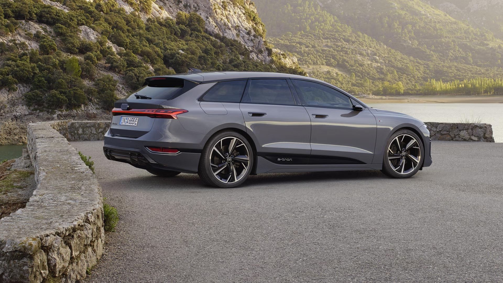 Ein grauer A6 Avant e-tron steht auf einem Platz vor einem Gewässer.