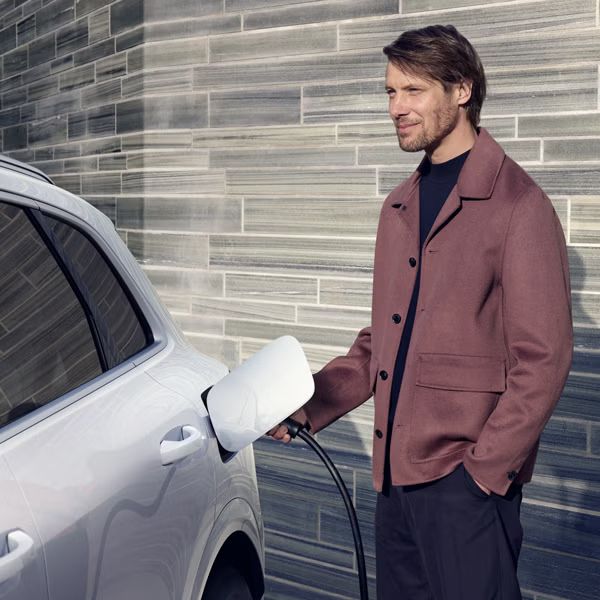 Ein Mann steckt ein Ladekabel an einem Audi Q5 SUV e-hybrid an